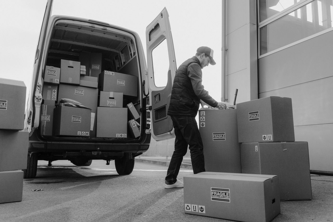 services-01 Delivery driver unloads packages from a van, organizing shipments outdoors.