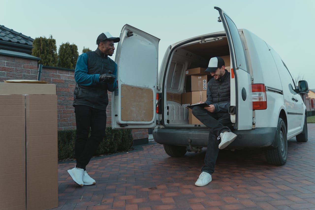 gallery-3 Two delivery workers loading packages into a van on a residential street.