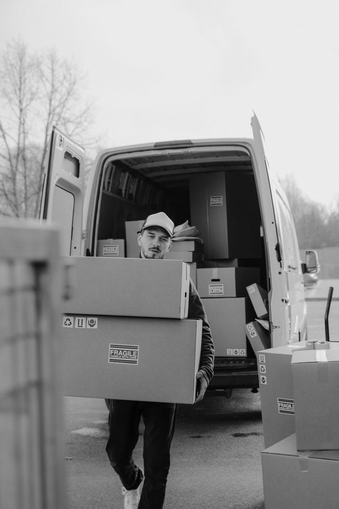 about-02 A courier carries cardboard boxes to a delivery van, ready for shipment.